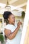 Focused happy senior african american woman painting canvas on easel at home