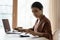 Focused Indian woman calculating and paying household bills, using laptop