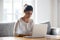 Focused Indian woman using laptop at home, looking at screen