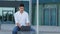 Focused Indian young businessman working on project, using portable laptop sitting outdoors. Concentrated male