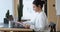 Focused indian young woman holding paper documents, working on computer.