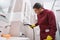 Focused janitor steam-cleaning grout line on bathroom wall