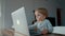 Focused little boy watches cartoons on modern laptop