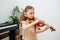 Focused little girl learning to play violin, hitting strings with her finger