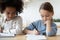 Focused little multiracial sisters preparing homework indoors.