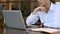 Focused male employee analyzing financial data on computer laptop.