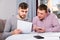 Focused males with phone and papers at home table