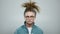 Focused man in glasses standing on grey background. Hipster posing in studio