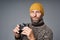 Focused mature man in warm sweater and knitted hat holding binoculars