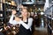 Focused mature woman wine producer inspecting quality of wine in wineshop on background with shelves of wine bottles