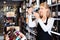 Focused mature woman wine producer inspecting quality of wine in wineshop on background with shelves of wine bottles