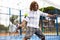 Focused middle-aged Latin man playing padel on court. View through tennis net