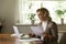 Focused middle aged woman holding document and using laptop