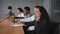 Focused multiracial employees sitting in conference room making different work tasks hispanic woman in foreground