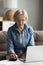 Focused older retired laptop user woman paying bills online