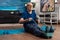 Focused pensioner sitting on yoga mat stretching legs muscle using fitness elastic band