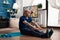 Focused pensioner wearing sportswear sitting on yoga mat stretching legs muscle