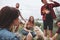 Focused photo. Group of people have picnic on the beach. Friends have fun at weekend time