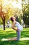 Focused pregnant woman doing yoga on mat in park