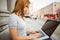 Focused pretty redhead typing on laptop