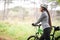 Focused on the road ahead. An attractive female cyclist walking alongside his bike.