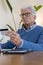 Focused senior man looking at laptop screen, holding bank card