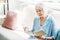 focused senior woman with glass of wine reading book on couch