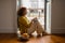 Focused senior woman sitting on floor by the balcony and using laptop