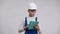 Focused serious boy in hard hat and overalls using tablet thinking and looking at camera. Portrait of confident
