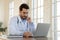 Focused serious young male doctor working on computer.