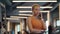 Focused sportswoman talking on phone at gym. Athlete girl standing in sport club