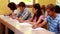 Focused students sitting in a line writing in classroom