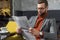 Focused stylish man in formal wear and glasses sitting and reading newspaper