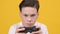 Focused Teen Boy Playing Video Game Over Yellow Studio Background