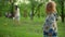 Focused toddler standing outside. Happy mother and son playing with ball in park