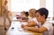 Focused tween boy writing exercises in classroom during lesson