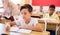 Focused tween boy writing exercises in classroom during lesson