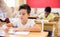 Focused tween boy writing exercises in classroom during lesson