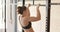 Focused unaltered caucasian woman training at gym doing pull ups on bars, in slow motion