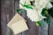 Focused White peony flowers bouquet and blurred blank greeting card and craft paper envelope on the old wooden rustic table backgr