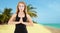 Focused white woman doing namaste mudra gesture in front of summer sea