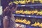 Focused woman in face mask choosing fruits, taking bananas from shelves in grocery store. Customer in supermarket. Side