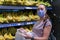 Focused woman in face mask choosing fruits, taking bananas from shelves in grocery store. Customer in supermarket. Side view.