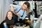 Focused woman hairdresser cutting hair of elderly female client