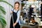 Focused woman hairstylist sweeping floor in hairdressing salon