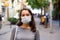 Focused woman in medical mask walking along city street