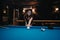 Focused woman playing pool in a dimly lit billiard hall with friends