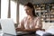 Focused woman working on laptop, sitting at desk at home