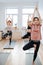 Focused women practicing yoga in a group of three, balancing on one foot