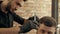 Focused young barber cutting hair to male client in hair salon